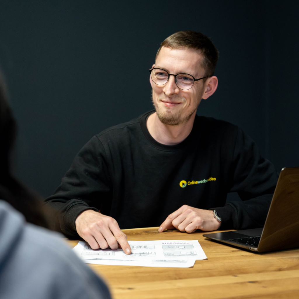 Der Mitarbeiter Stefan Kinzel von der Videoproduktion Onlinewerbevideo im Gespräch mit einem Kunden, er lächelt freundlich und berät zur Konzeptionsentwicklung für einen professionellen Videodreh im Kundenunternehmen