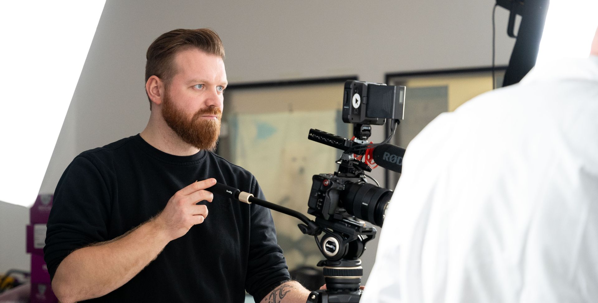 Hochkonzentrierter Mitarbeiter einer Videoproduktionsfirma steht vor einer großen professionellen Kamera während eines laufenden Streamings, professionelle Videoproduktion Dresden für Onlinewerbevideo und Livestream Formate